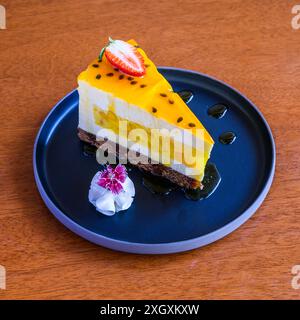 Delicious passion fruit cake decorated with fresh fruit and whipped cream on a blue plate Stock Photo