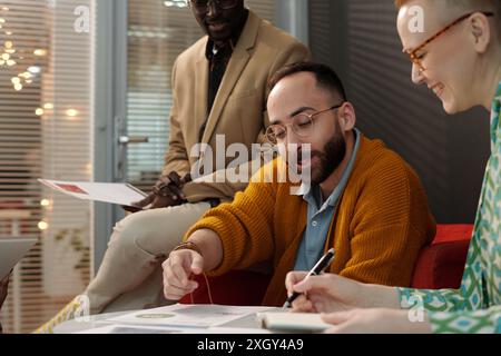 Intercultural business professionals working together at meeting, and discussing project points while bearded man explaining data Stock Photo