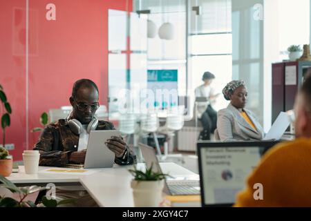 Professionals engaging in office meeting, reviewing reports and sharing ideas in collaborative environment Stock Photo