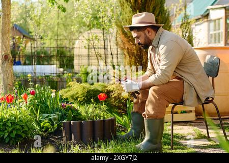 Side view of serious mature male farmer in workwear looking at smartphone screen while texting or watching online video Stock Photo