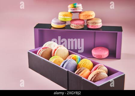 Colorful macarons of different flavors in boxes on a pink background with shadow. Stock Photo