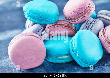 Multi-colored macarons of blue cheese and blueberry flavors on blue concrete are stacked in a slide. Stock Photo