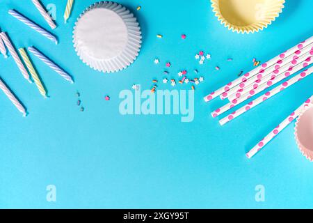 Cupcake liners, candles, and confetti on a blue background, party preparation. Stock Photo