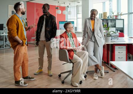 Group of diverse professionals collaborating on business tasks in modern office, emphasizing teamwork and inclusivity Stock Photo