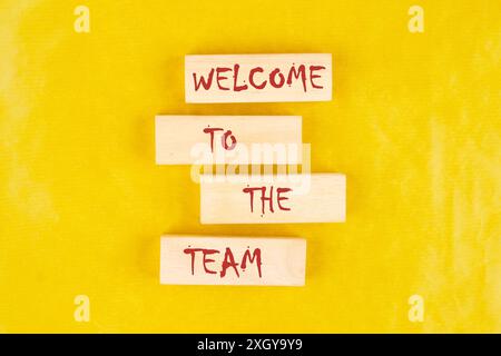 Welcome to the team. Text on wooden blocks on a bright yellow mustard background Stock Photo