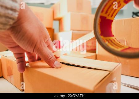 Goods delivery concept , Human hand packs merchandise into cardboard box for delivery to a customer Stock Photo