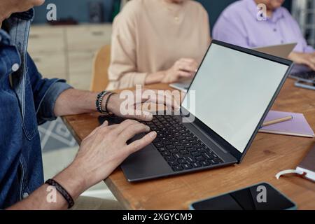 Side view closeup of senior man using laptop with blank white screen in computer class for elderly with focus on hands typing copy space Stock Photo
