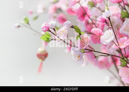 Beautiful artificial cherry blossom tree. Traditional Asian decoration. Pink and white flowers of Sakura. Oriental Chinese red lantern is visible in b Stock Photo