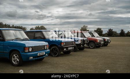 Three Range Rovers and two Land Rover Discoveries in a line at a classic car meet. Stock Photo