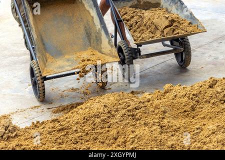 Workers dump sand from wheelbarrows onto the pile Stock Photo