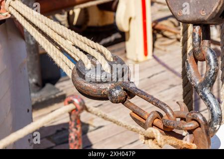 Sailing ship lines, pulleys and securing equipment tied down for the day. Deck and ropes, rigging on a wooden tall ship sail yacht. Close up view Stock Photo