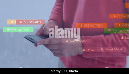 Image of social media icons floating against mid section of man using smartphone Stock Photo