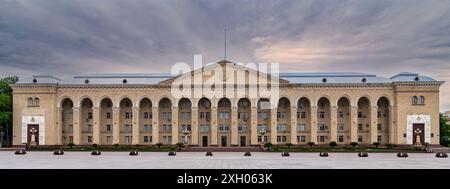 Wide shot of Ganja City Hall, Azerbaijan, a large beige building with arched facade, many windows, central entrance, in front of a big plaza Stock Photo