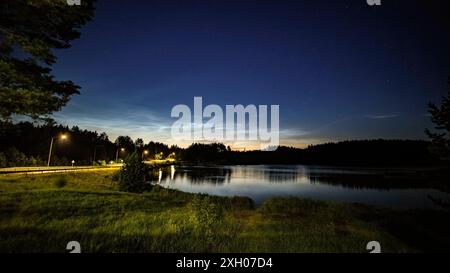 Lake at night, sky with stars, reflection in water, noctilucent clouds Stock Photo