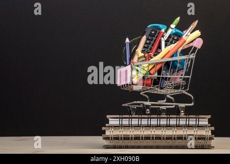 back to school template with multiple stationery in trolley with copy space against black background. education concept background with copy space. Stock Photo