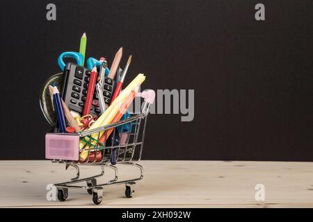 back to school template with multiple stationery in trolley with copy space against black background. education concept background with copy space. Stock Photo