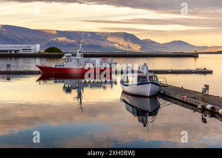 Two boats reflecting  water reykjavik harbor sunset  mountains background Stock Photo