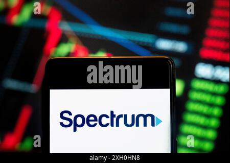 In this photo illustration, the American telecommunications company owned by Charter Communications, Spectrum (NASDAQ: CHTR), logo seen displayed on a smartphone with an economic stock exchange index graph in the background. (Photo by Budrul Chukrut / SOPA Images/Sipa USA) *** Strictly for editorial news purposes only *** Stock Photo