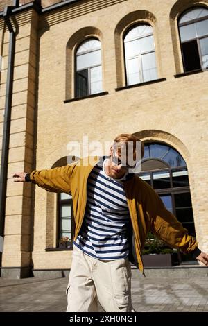 Stylish man with red hair taking walking in city sidewalk. Stock Photo