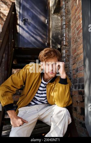 Red-haired man in debonair attire sits on stairs. Stock Photo