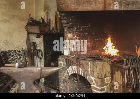 This atmospheric photograph captures the rustic charm of a blacksmith's forge, complete with an anvil, glowing fire, and an array of traditional tools Stock Photo