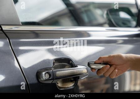 A young woman's hand is pressing a remote to lock her car Stock Photo