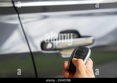 A young woman's hand is pressing a remote to lock her car Stock Photo