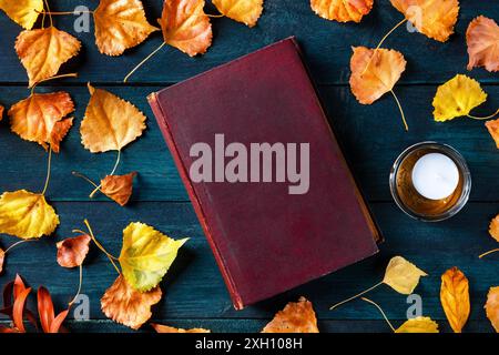 Autumn book cover mockup, an old book with fall leaves, flatlay top shot on a dark blue wooden background Stock Photo