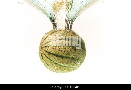 Cantaloupe melon splashing into water isolated on white background. Healthy food concept Stock Photo