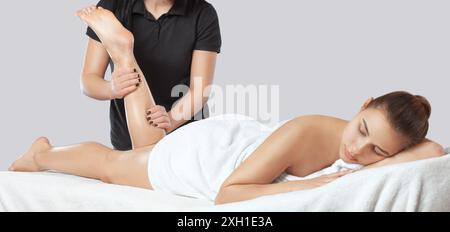 An orthopedic doctor does massage of the foot and lower leg of the patient after an injury in the clinic.Cosmetology and massage concept.Cosmetology a Stock Photo