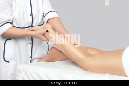 An orthopedic doctor does massage of the foot and lower leg of the patient after an injury in the clinic.Cosmetology and massage concept.Cosmetology a Stock Photo