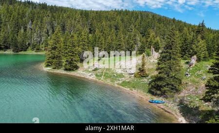 Aerial view of a kayak on the beautiful teal blue waters of Crystal Lake, surrounded by pine trees. Lewis and Clark National Forest, Montana Stock Photo