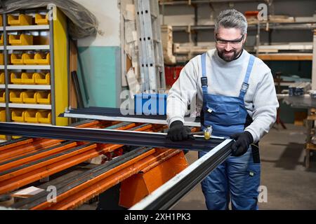 Master in overalls works with awindow frame made of aluminum profile Stock Photo