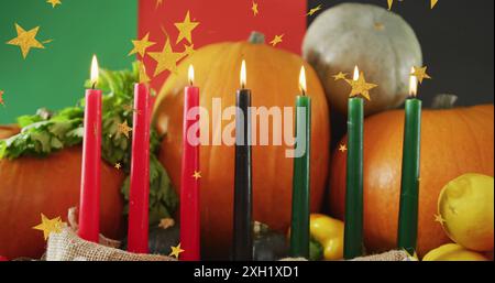 Image of golden stars over kwanzaa candles and pumpkins. Kwanzaa festivity, celebration and tradition concept digitally generated image. Stock Photo