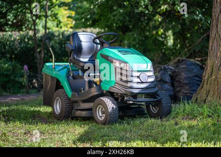 Modern lawn mower, petrol, gasoline powered garden tractor with seat, steering wheel to trim grass Stock Photo