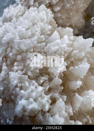 Detailed close-up image showcasing the intricate and natural white salt crystal formations with rough texture. Stock Photo