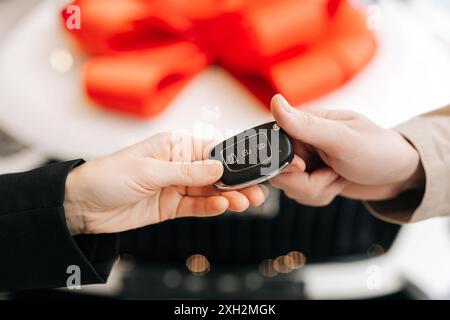 Closeup cropped shot of unrecognizable female seller giving car key and congratulating to male after successful deal in auto dealership Stock Photo