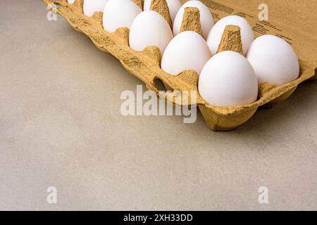 Close-up from above of free-range eggs in a cardboard egg carton on a gray background Stock Photo