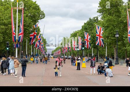 London, England - June 01 2024: Road near Buckingham palace lined with union jack flags and many tourists in spring overcast day Stock Photo