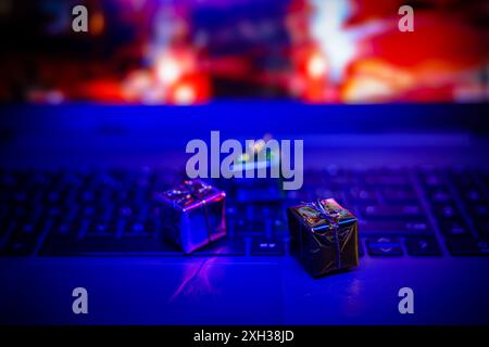 Small gifts rest on a laptop keyboard with colorful blurred lights in the background. Stock Photo
