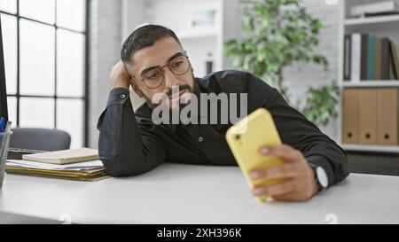 Handsome arab man in glasses using smartphone at office desk Stock Photo