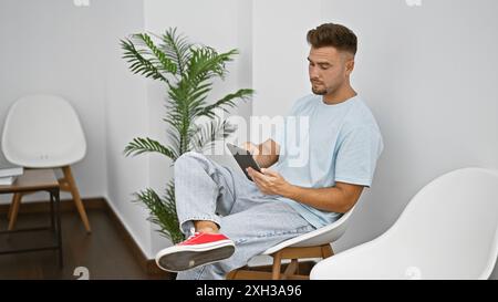 Handsome hispanic man using tablet in a modern waiting room. Stock Photo