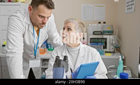 A man and woman in a laboratory setting examining scientific equipment and data together. Stock Photo