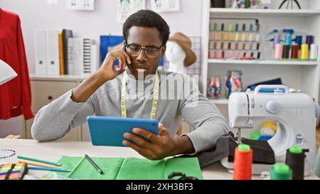 African american man talking on the phone while holding a tablet in a modern tailor shop. Stock Photo