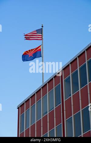 American flag, Arizona state flag waving above office building in late evening light Stock Photo