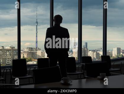Man looking through office window on Moscow Ostankino TV tower in Russia. Panorama of the Russian city during sunset Stock Photo