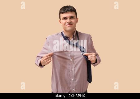 Stressed young man with coffee stains on his shirt on beige background Stock Photo