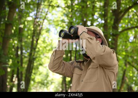 Forester with binoculars examining plants in forest Stock Photo
