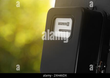 Electricity meter on wall outdoors, space for text. Measuring device Stock Photo