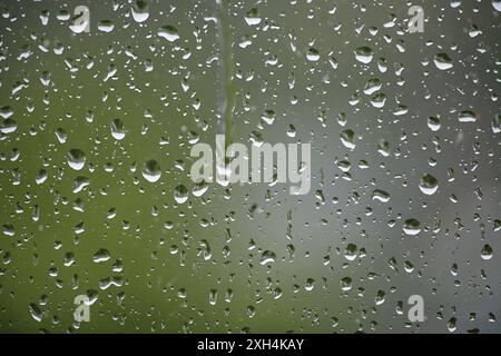 The raindrops on the window are small and numerous. Concept of calm and peacefulness, as the raindrops create a soothing sound as they fall on the gla Stock Photo